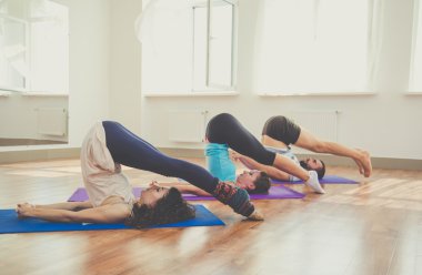 Group of persons are doing yoga indoors