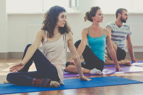 Sportive three persons are doing yoga indoors — Stockfoto