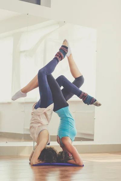 Two slim girls are doing acroyoga in studio — Stockfoto