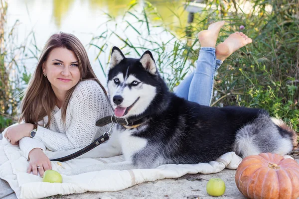 Girl and her husky dog is lying near green river — Stock Photo, Image