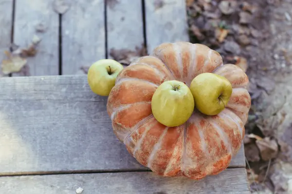 Pumpkin and green apples lying on woods — Stock Photo, Image