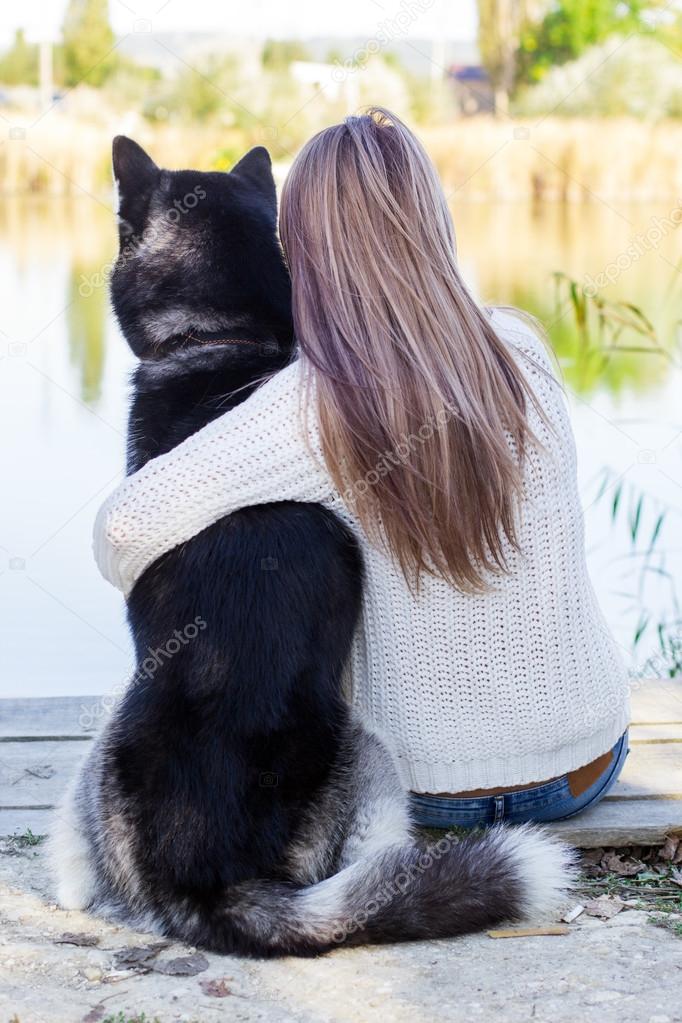 Back view of girl is hugging husky dog outdoors