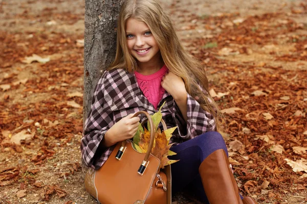 Linda chica sonriente con bolsa llena de hojas de otoño — Foto de Stock