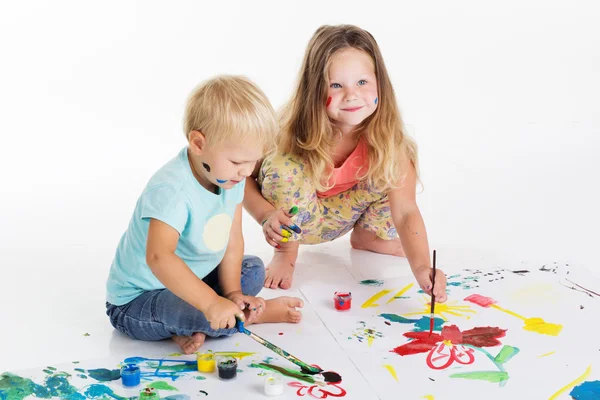 Två childs ritar av aquarelle färger på vitt papper Stockfoto