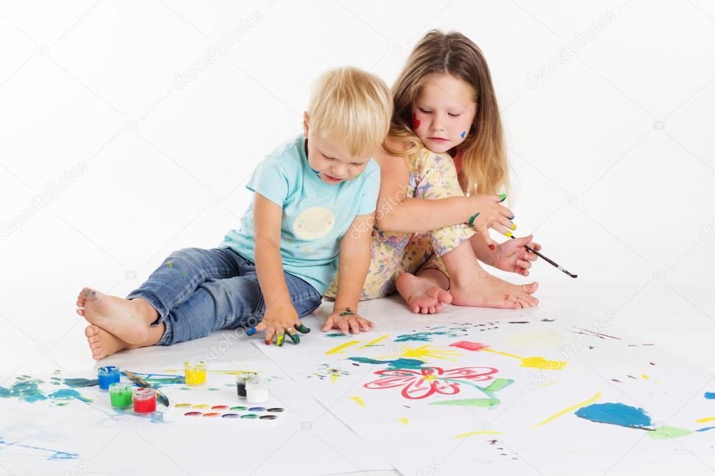 Two childs are drawing by aquarelle paints