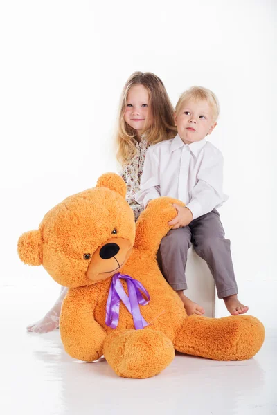 Paar mädchen und junge haben spaß mit groß teddy bär — Stockfoto