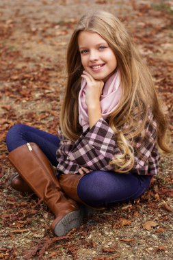 Sevimli kız sonbahar Park yeşillik oturuyor