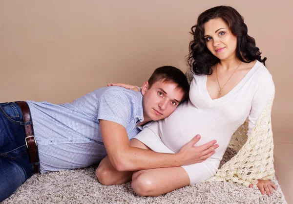 Pregnant girl and boy are posing in studio — Stock Photo, Image