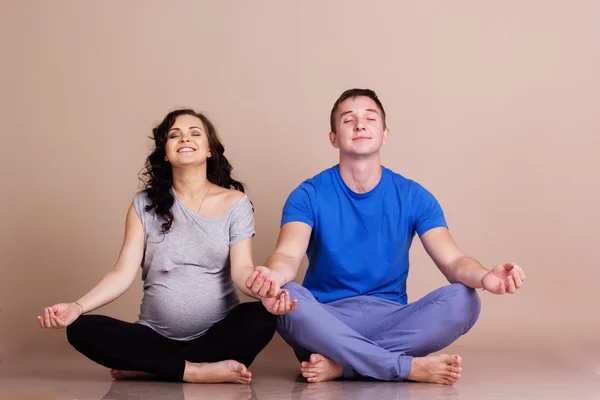 Ragazza incinta e uomo che fa yoga — Foto Stock