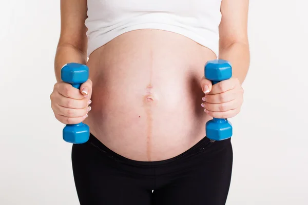 Belly of pregnant woman with dumbbells — Stock Photo, Image