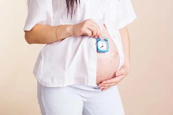 Ventre de la femme enceinte avec des horloges — Photo