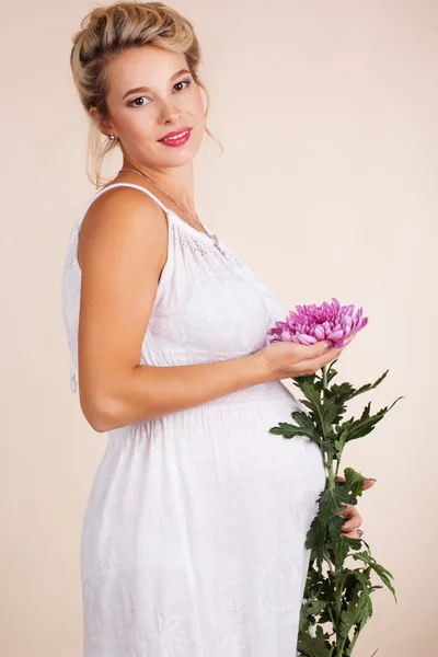 Mujer embarazada con flor rosa de margarita dorada —  Fotos de Stock