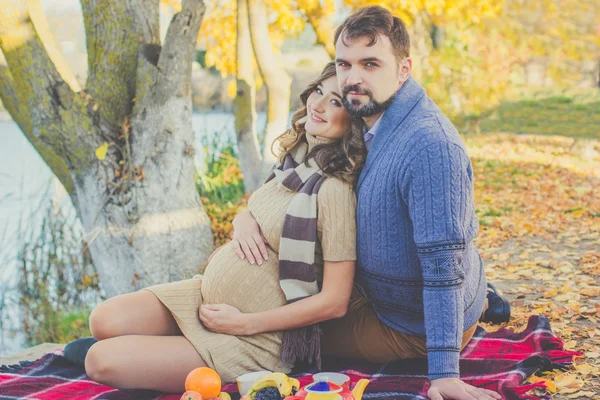 Man and pregnant woman are sitting near lake — Stock Photo, Image