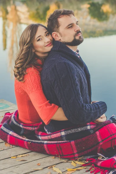 Couple are wrapped in warm blanket near lake — Stock Photo, Image