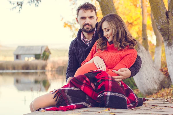 Pregnant happy woman and man are resting near lake — Stock Photo, Image