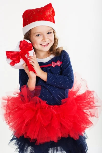 Smiling santa girl is holding red gift box — Stock Photo, Image