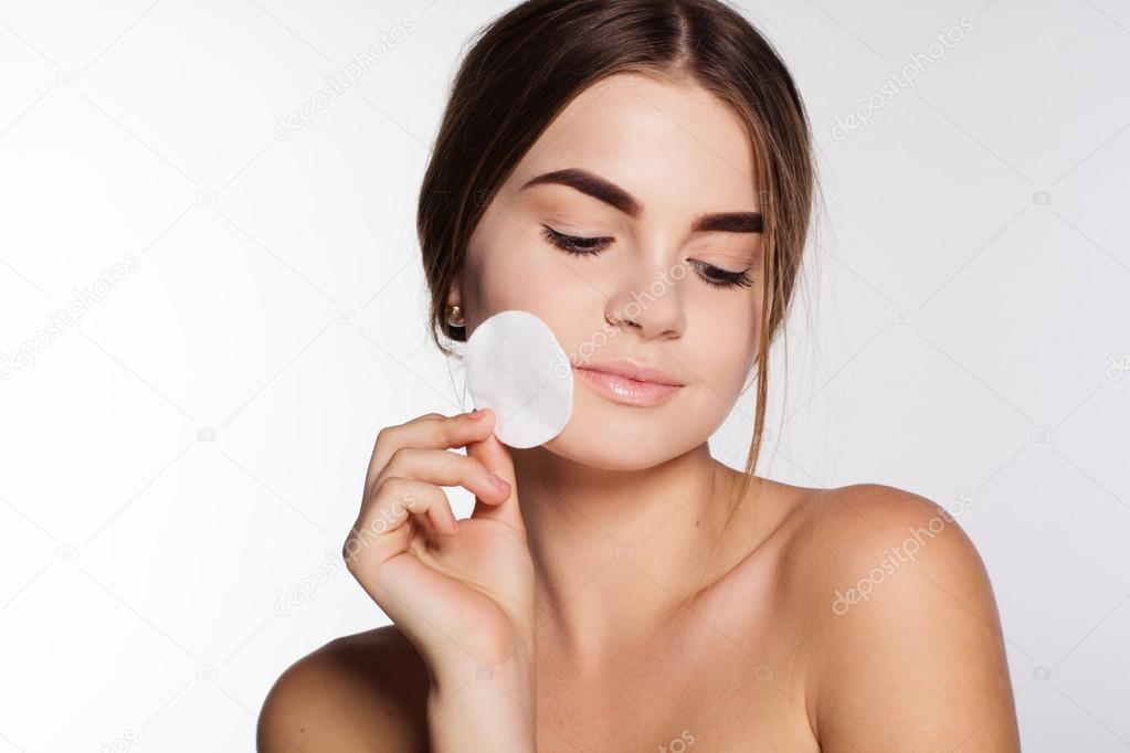Beautiful girl is remove makeup with cotton wool