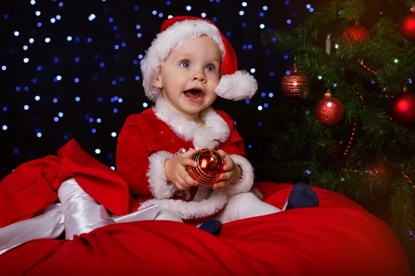 Bébé heureux avec boule de Noël rouge près du sapin — Photo