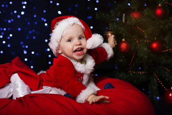 Happy baby is sitting near Christmas fir-tree — Stock Photo, Image