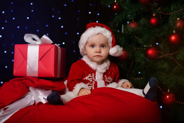 Joyeux bébé est assis près de sapin de Noël avec des cadeaux — Photo