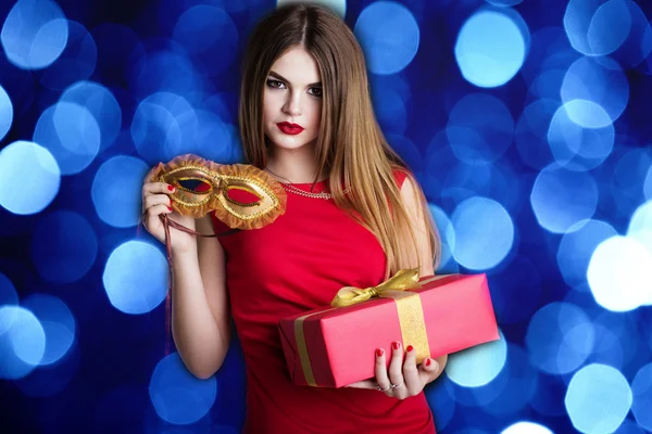 Pretty girl is holding red gift box and mask — Stok fotoğraf