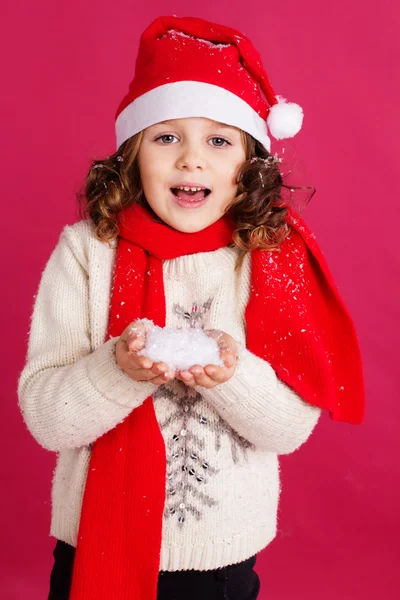 Маленькая девочка в шляпе Санты держит фальшивый снег — стоковое фото