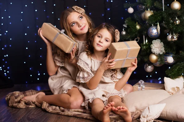 Two girls are sitting near christmas tree — Stock Photo, Image