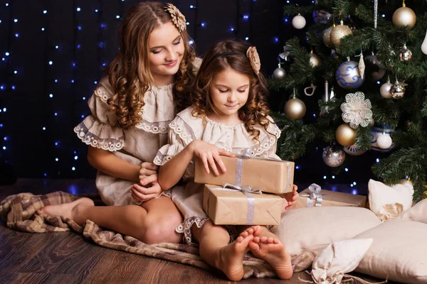 Two girls are sitting near christmas tree at home — Stock Photo, Image