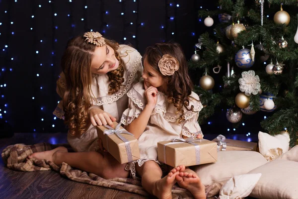 Deux filles sont assises près de l'arbre de Noël à la maison — Photo