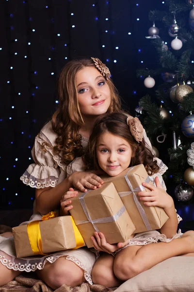 Two girls friends with gifts near christmas tree — Stock Photo, Image