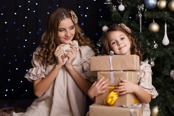 Two girls friends with gifts near christmas tree — Stock Photo, Image