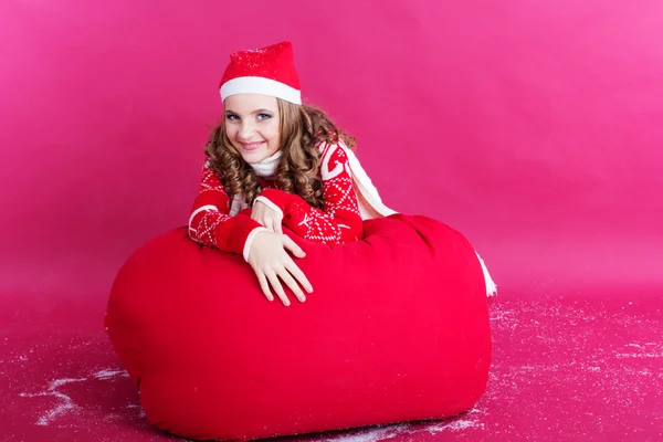 Κορίτσι είναι ξαπλωμένος σε μεγάλη κόκκινη τσάντα Χριστούγεννα — Φωτογραφία Αρχείου