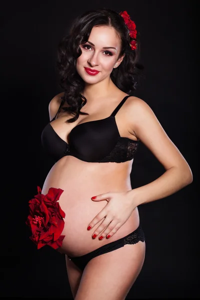 Беременная девочка с цветком розы на животе — стоковое фото