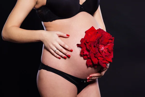 Red rose flower on womans pregnant belly — Stock Photo, Image