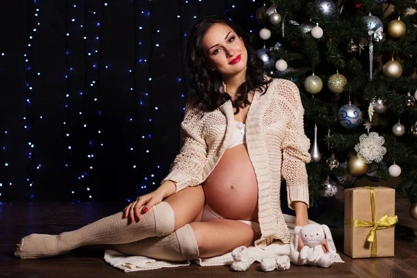 Gravid kvinna hemma semester nära julgran, — Stockfoto