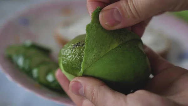 Womans Hands Taking Out Pulp Of Avocado. Cleaning avocado with hands