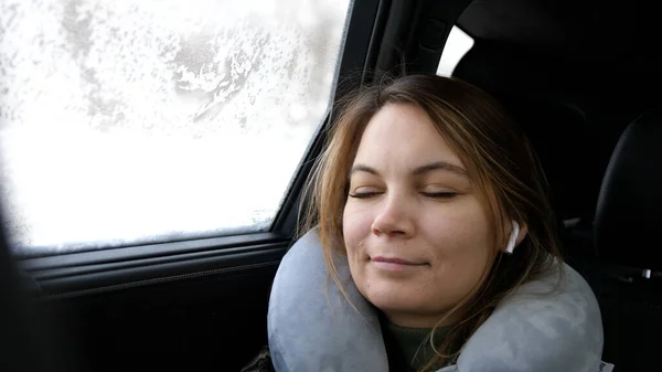A girl rides in the car sleeps with headphones in her ears. 4k