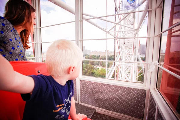 Mom and her son rolling on the Ferris wheel, look out window
