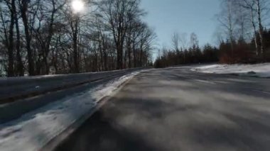 Motorsikletten çekilmiş güneşli bir kış sokağı.