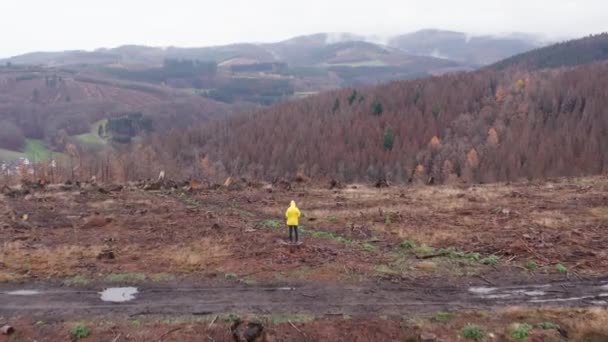 4Kの秋の森の丘の風景に黄色のジャケットを着た男 — ストック動画
