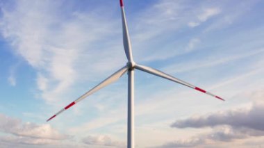 4K 'da güneşli bir gökyüzünün önünde modern bir rüzgar türbini.