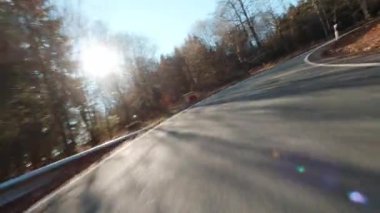 Bir motosiklet pov 'undan çekilmiş güneşli bir cadde.