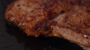 Sulu bir biftek tavada kızarıyor. 