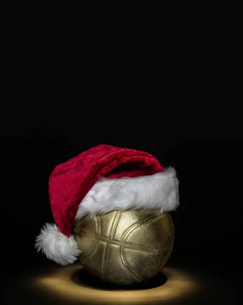 黒い背景を持つパケットの上にサンタの帽子付きの黄金のバスケットボールボール ストック写真