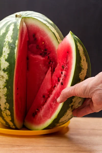 Hand met een groot stuk van watermeloen — Stockfoto