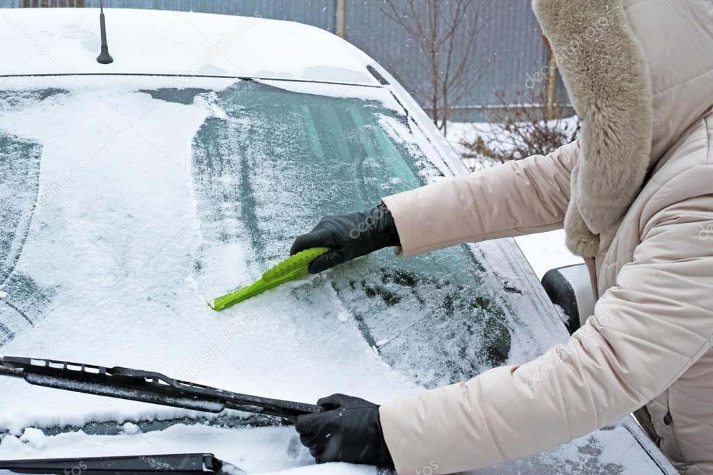 Woman remove snow from windshield