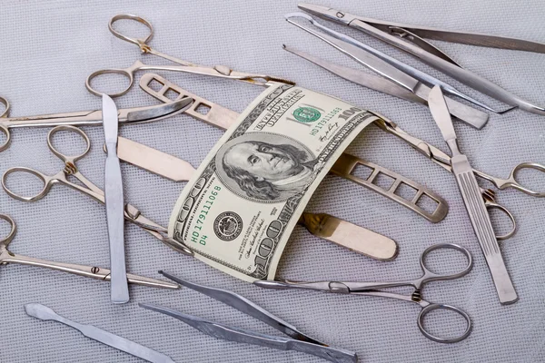 Hundred dollars and surgical instruments — Stock Photo, Image