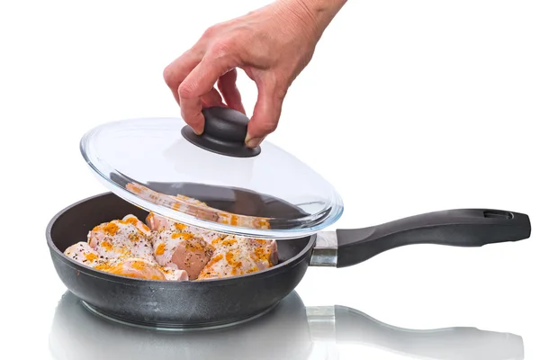 Chicken legs in a frying pan with glass lid — Stock Photo, Image