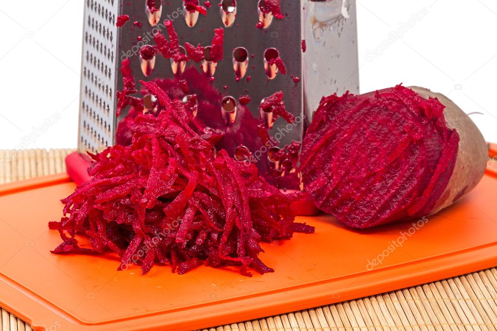 Pile of grated red beets and grater closeup