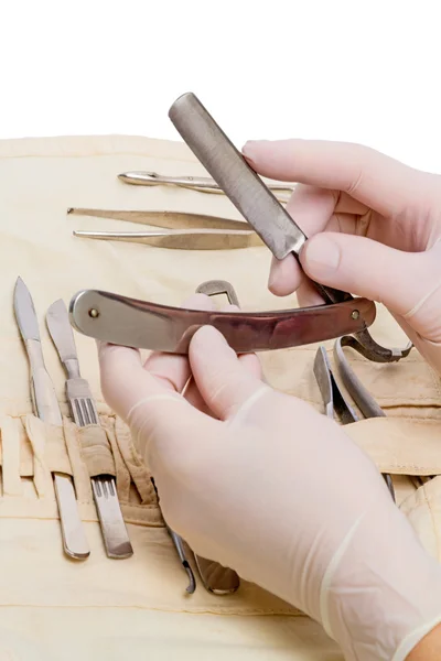 Hand met scheermes en chirurgische instrumenten — Stockfoto